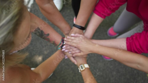 Sport teamwork concept. Group of women stacking hands together during running workout in park