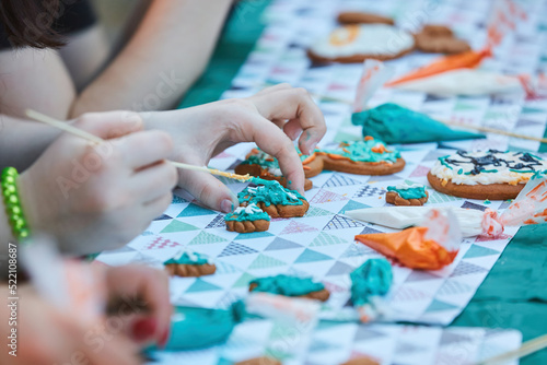 A teenager's hand is decorating a gingerbread. Delicious and creative activity for children and adults.