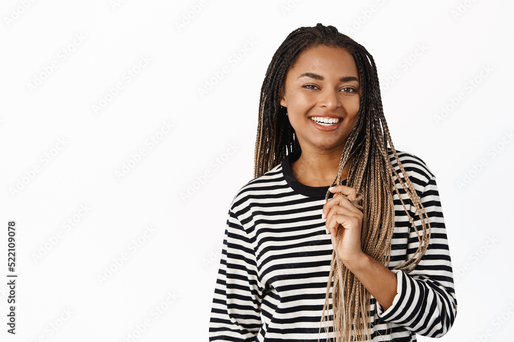 Beautiful female model with dreads, smiling and laughing, playing with braids, standing over white background Beautiful female model with dreads, smiling and laughing, playing with braids, standing over white background