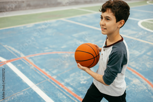 12 year old boy playing basketball. Teenager training basketball outdoors. © kleberpicui