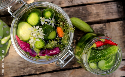 Фотография pickles in a jar with bitter pepper and inflorescence of wild garlic on a wooden