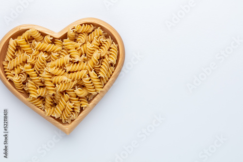 Pasta in a heart shaped wood bowl.