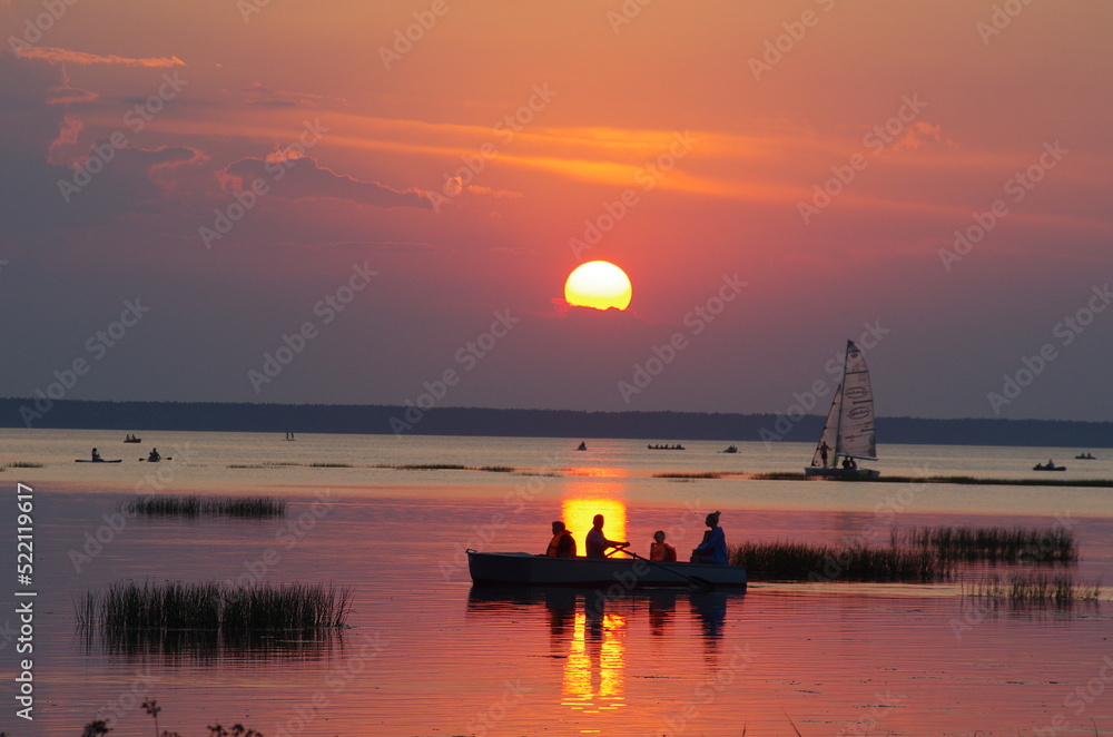 Wooden boat crossing sunlight on the sunset lake