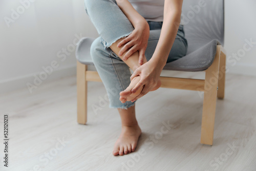 Closeup shot of pain leg foot suffering tanned beautiful young Asian woman touch ankle at home interior living room. Injuries Poor health Illness concept. Cool offer Banner