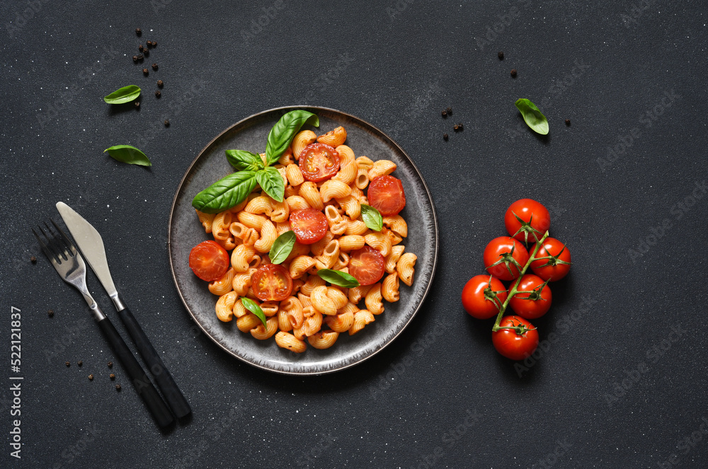 Pasta with tomato sauce and cherry tomatoes on a concrete background, top view, with space for text