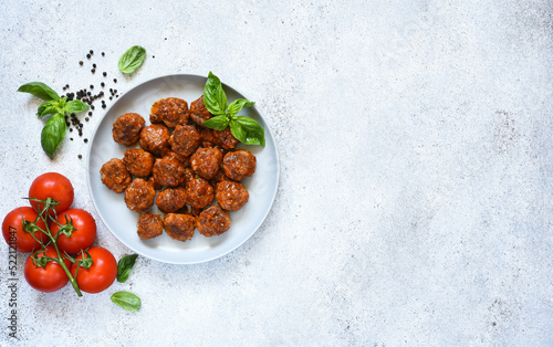 Meatballs with tomato sauce and basil in a plate, top view with space for text