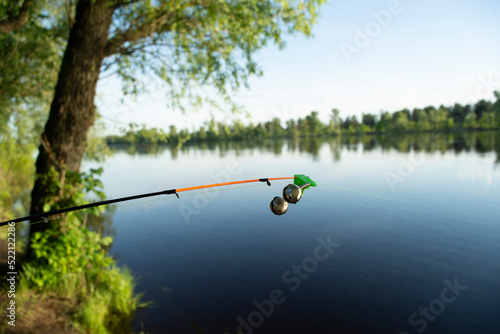 bell alarm is on fishing rod spinning in nature bells of allure are attached to the end of the fishing spinning abandoned in water standing with stretched fishing line Bottom rod and fishing accessori photo
