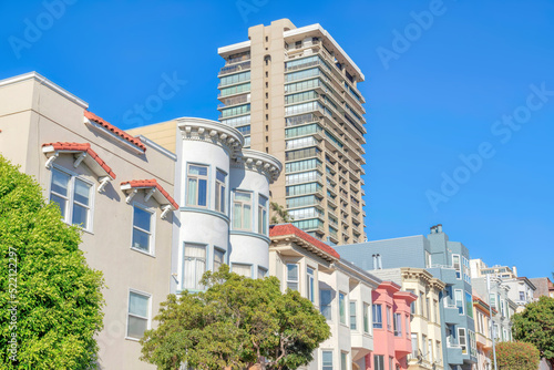 Row of victorian style apartments and a high-rise building with railings at San Francisco, CA