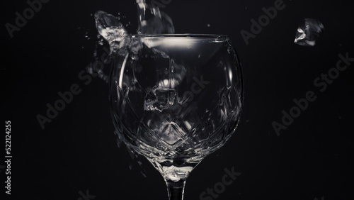 Ice cubes lemons falls empty wineglass closeup. Refreshing drink concept