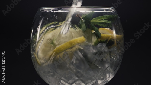 Jet water filling lemon mint wineglass closeup. Preparing homemade drink concept