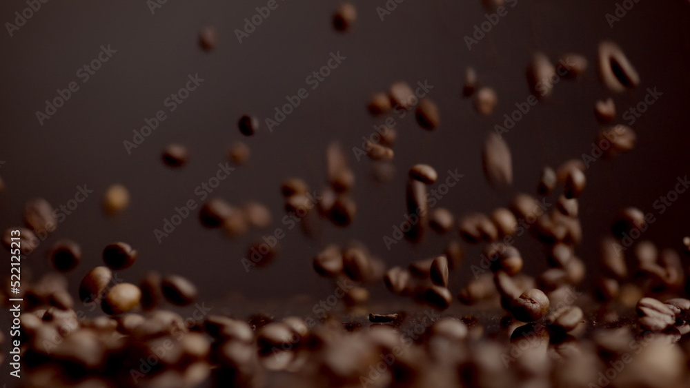 Brown coffee grains falling on surface bouncing closeup. Dawnfall roasted seeds. Brown coffee grains falling on surface bouncing closeup. Dawnfall roasted seeds.