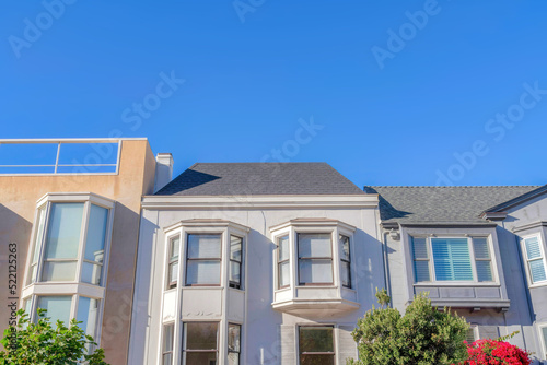 Facade of adjacent houses with bay windows against the blue sky at San Francisco, CA © Jason