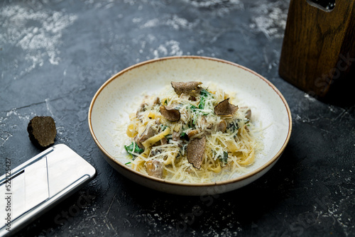 pasta with porcini mushrooms and truffle with spinach on dark stone table photo