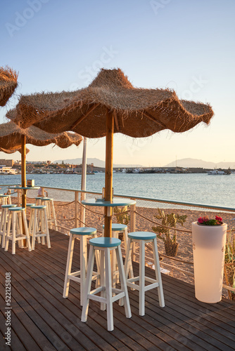 View on empty bar table against sunset at the beach. Summer time in Italy