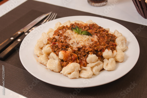 Detail view of a plate of gnocchi with sauce and grated cheese.