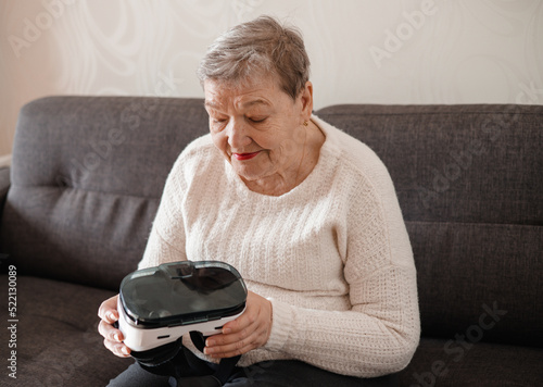 An elderly woman is looking at virtual reality glasses. Modern technologies. New experience in old person\'s life. Adaptation of pensioners in modern world. The idea of original gift for Mother\'s Day
