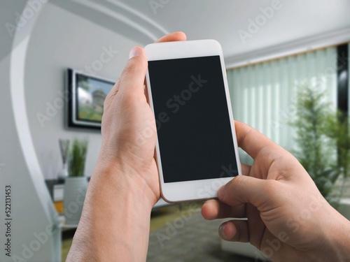 Smart home concept.  Woman holding mobile phone on home interior background. Internet of things, comfort in house