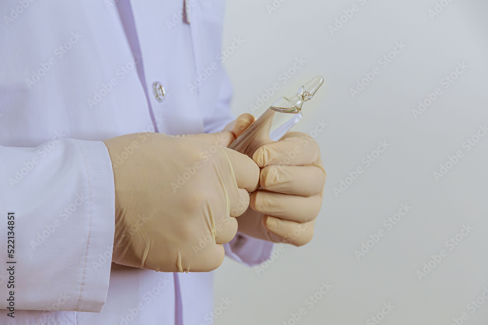 The doctor holds an ampoule with medicine in his hands on a white background.
