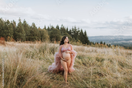 Pregnant Woman Wearing Pink Robe Walking through Field photo