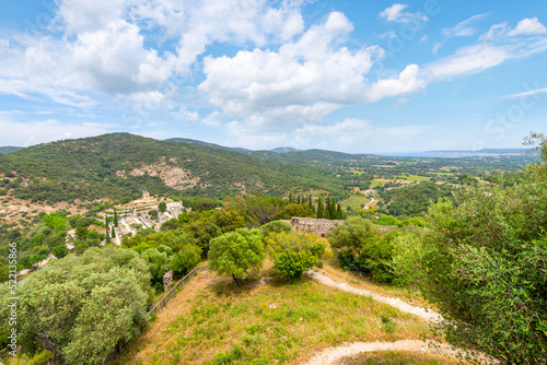 View from the walls of the hilltop medieval castle with the Saint-Roch Gardiole windmill, Grimaud cemetery and the town of Port Grimaud and Mediterranean sea in view. 