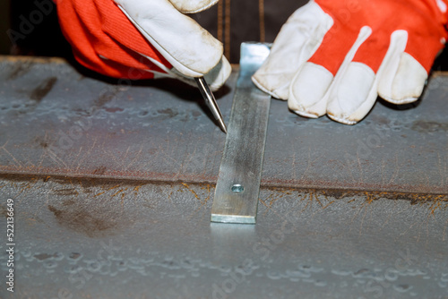 The worker makes a mark on a metal surface by means of Measuring square. Drilling holes in metal.