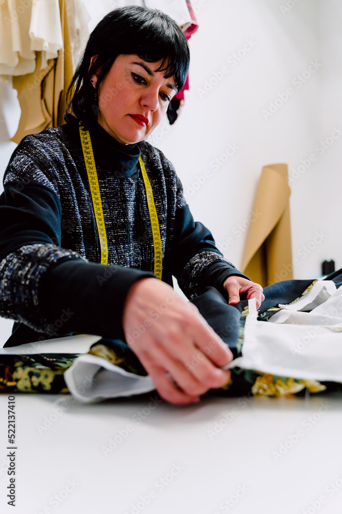 Dressmaker woman measuring the garments to design them.