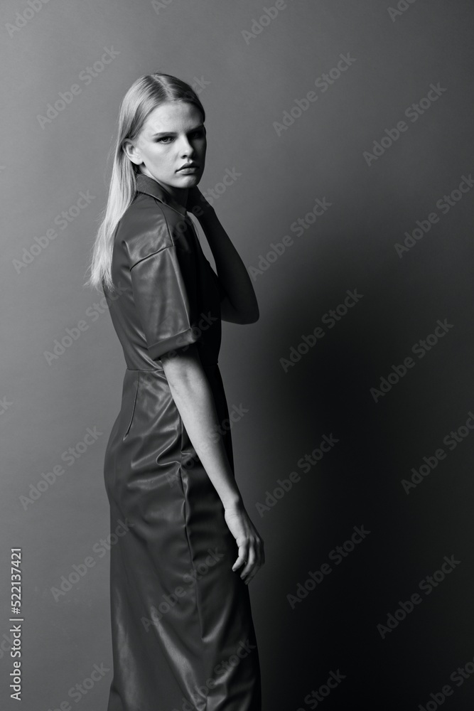 Fototapeta premium Fashion cool offer. Beautiful confident young woman looks over her shoulder at camera posing at studio background. Black and White concept. Art fashion photoshoot