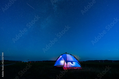 the blue tent is on the grassland. The tent is under the stars