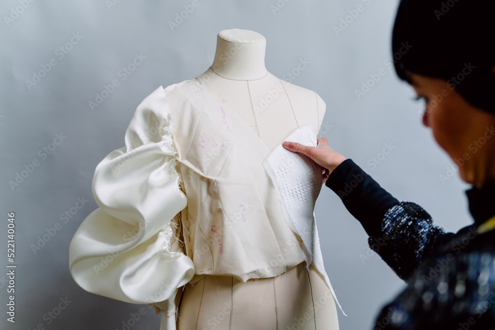 Dressmaker woman trying on the mannequin her designed clothes.