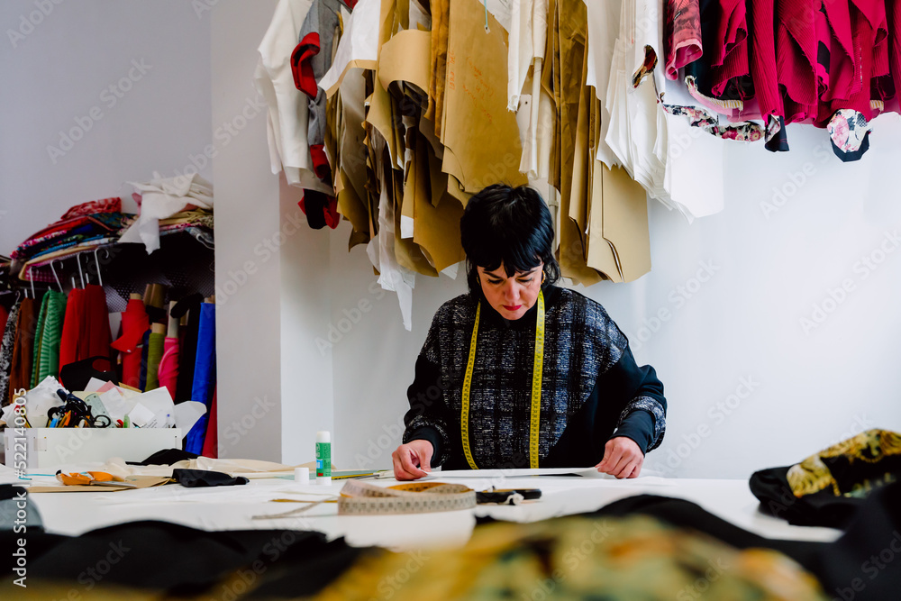 Dressmaker woman measuring the garments to design them.