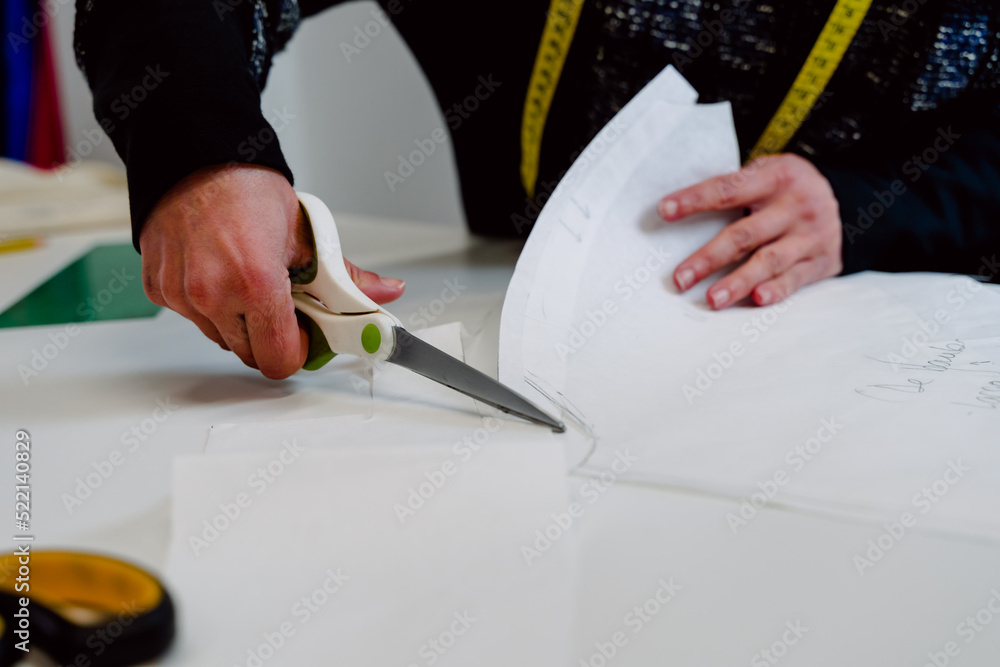 Dressmaker with scissors cutting cloth.