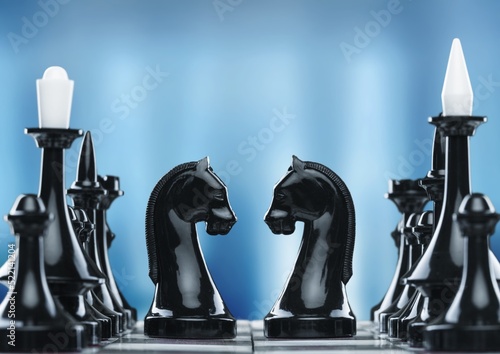 Shiny chess figures standing on wooden chessboard. Intellectual duel and tactical battle symbol. Strategy planning and corporate leadership concept.