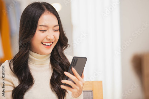Asian girl using smart phone playing game and social media or chatting with her friends. © sopradit