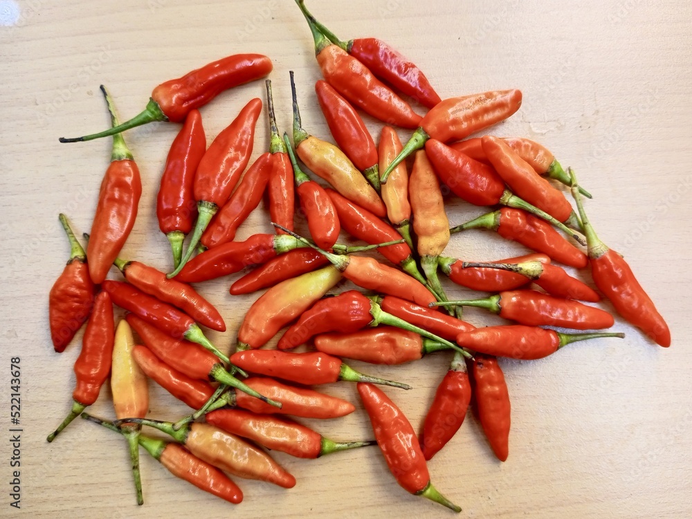 Some hot red chilies are placed on a brown wooden board Some hot red chilies are placed on a brown wooden board