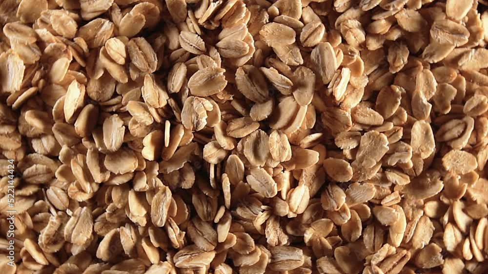 Oat Flakes Background Slowly Rotating Left - Top View, Low Key Light. Scattered Dry Oat Flakes. Healthy Breakfast and Diet Eating Ingredients Oat Flakes Background Slowly Rotating Left - Top View, Low Key Light. Scattered Dry Oat Flakes. Healthy Breakfast and Diet Eating Ingredients