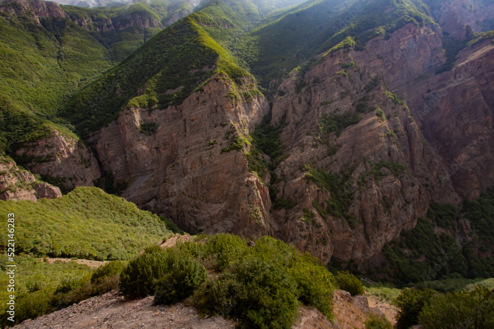 Obraz premium Breathtaking Cliff Surrounding The Valley Covered With Trees Grown Inside And On The Surface of Flat Rocky Mountain That Touches The Clouds In The Sky With Sun Rays, At Mazandaran Province, Iran.