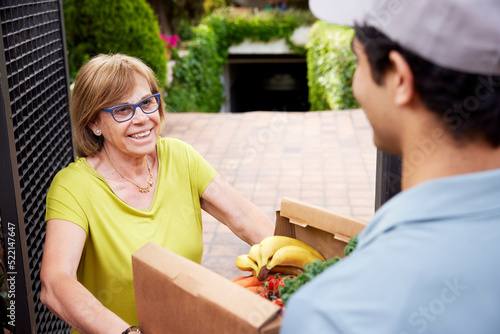 Mature woman receiving groceries from delivery man photo