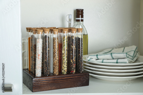 Glass tubes with different spices in kitchen cabinet