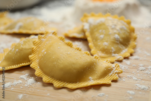 Raw ravioli on wooden board, closeup view. Italian pasta