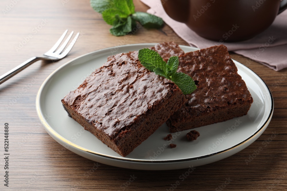 Delicious chocolate brownies with fresh mint served on wooden table, closeup