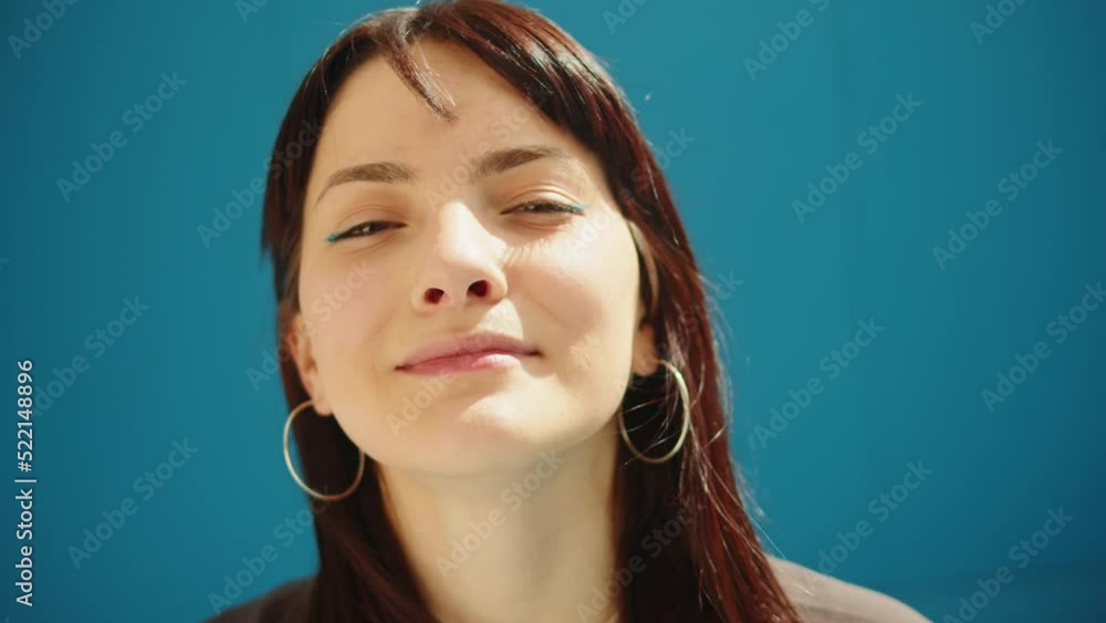 Young woman portrait. Happy street dancer smiling close-up. Female cheerful student posing on blue background wall outdoor, looking at camera. Young woman portrait. Happy street dancer smiling close-up. Female cheerful student posing on blue background wall outdoor, looking at camera.