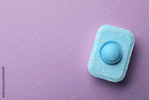 Water softener tablet on violet background, top view. Space for text