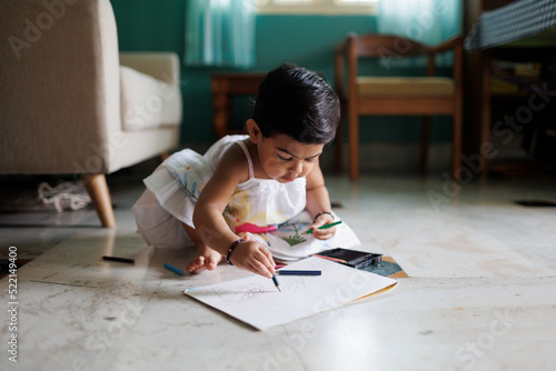 Cute little girl playing with color pencils, learning to draw photo