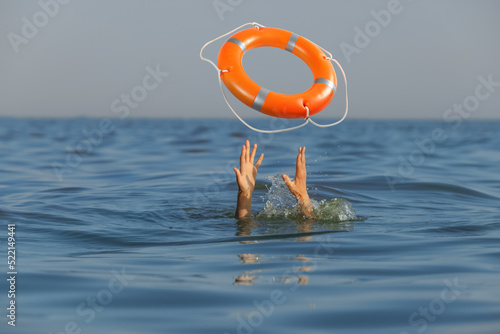 Drowning woman with raised hands getting lifebelt in sea