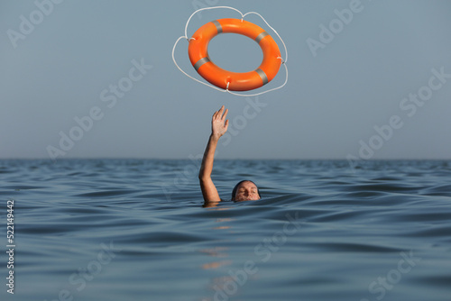 Drowning woman with raised hand getting lifebelt in sea