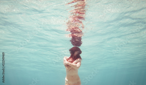 Cinematic portrait of woman holding herself underwater