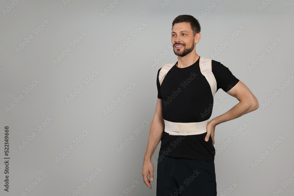 Handsome man with orthopedic corset on grey background, space for text Handsome man with orthopedic corset on grey background, space for text