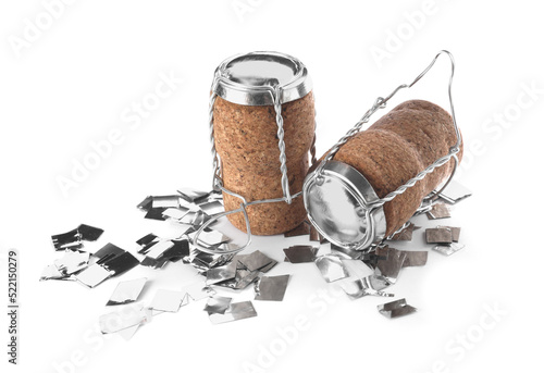 Corks of sparkling wine with muselet caps and shiny silver confetti on white background
