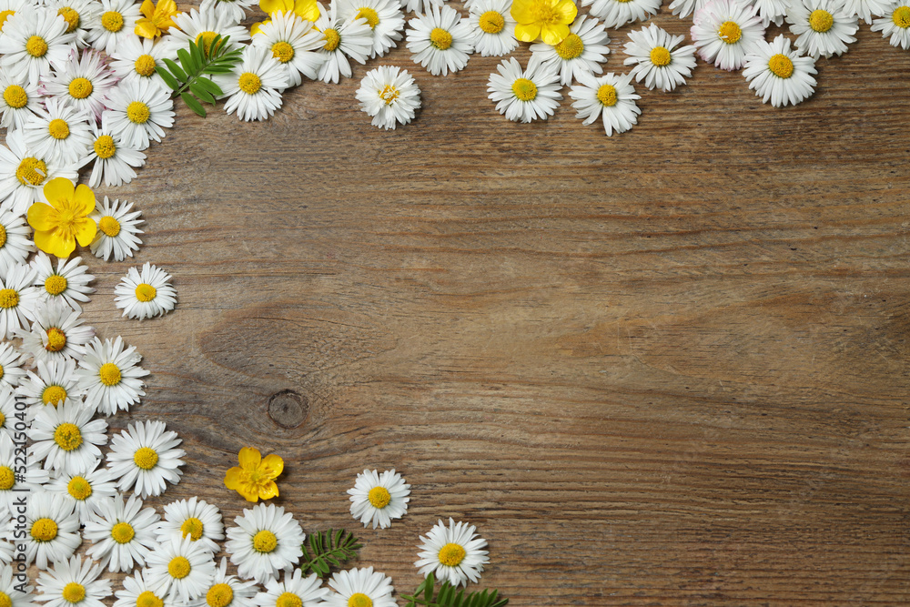 Obraz premium Beautiful flowers and leaves on wooden table, flat lay. Space for text