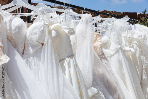 Clothing rack with hanging white wedding dresses photo